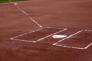 A close-up of the batters boxes and home plate on a vacant baseball diamond. © Can Stock Photo / ca2hill