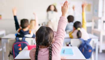 Students raising their hands in a classroom (Photo by: Jacob Wackerhausen/ iStock / Getty Images Plus)